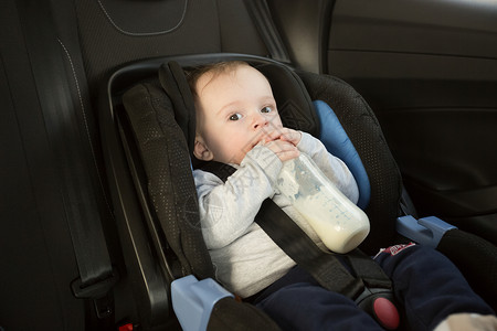 在汽车儿童座位上喝牛奶的男孩图片