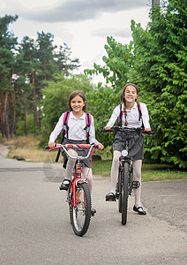 两个微笑着的女孩骑自行车上学图片