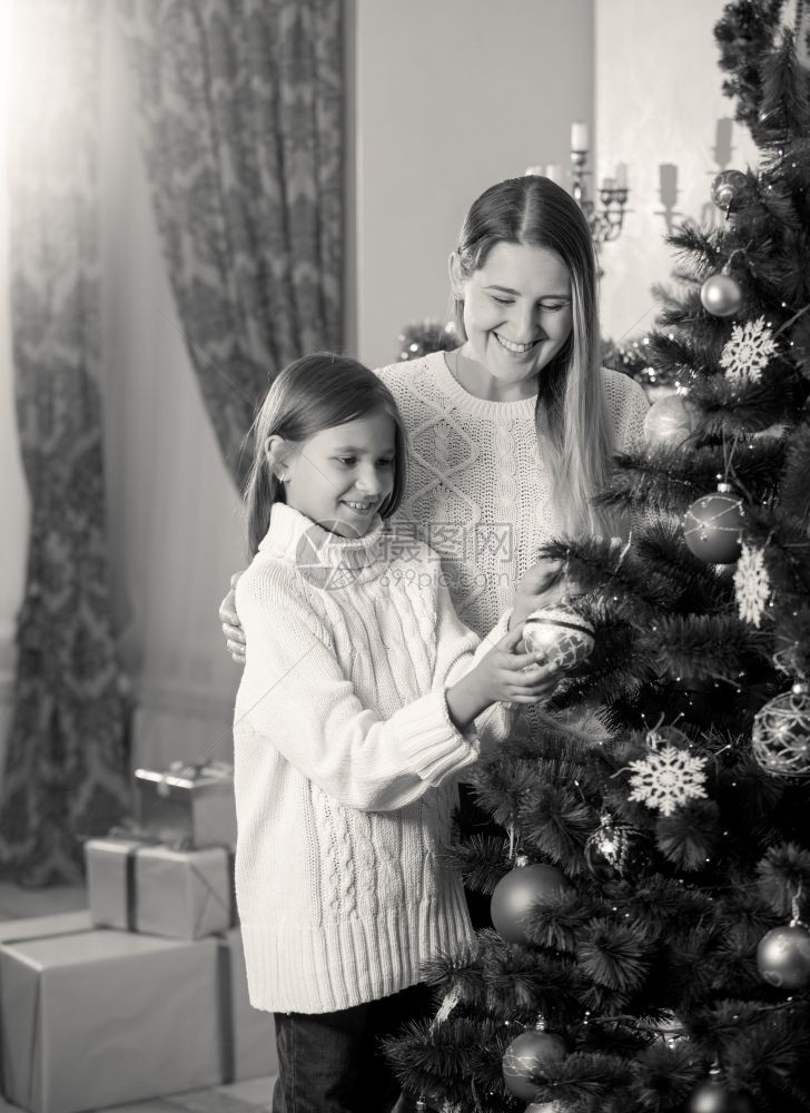 女儿帮助母亲装饰圣诞树的黑白照片图片