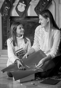 女儿在壁炉上包装圣诞礼物的幸福母亲黑白画像图片