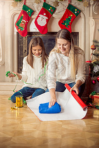 在圣诞节前夕快乐的女儿和母亲在包装纸上毛衣图片