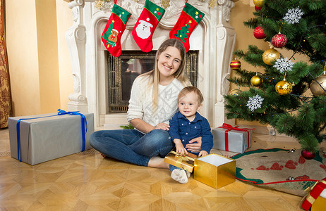 母亲和小儿子一起坐在地板上圣诞节装饰的客厅里图片