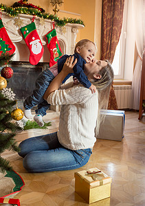 快乐笑的母亲和一岁大的儿子在圣诞树上摆姿势图片