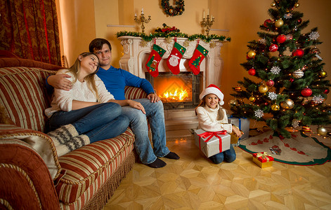 圣诞快乐的年轻家庭在壁炉附近放松图片