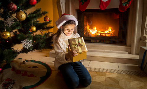 坐在燃烧的壁炉里看着圣诞礼物盒里图片