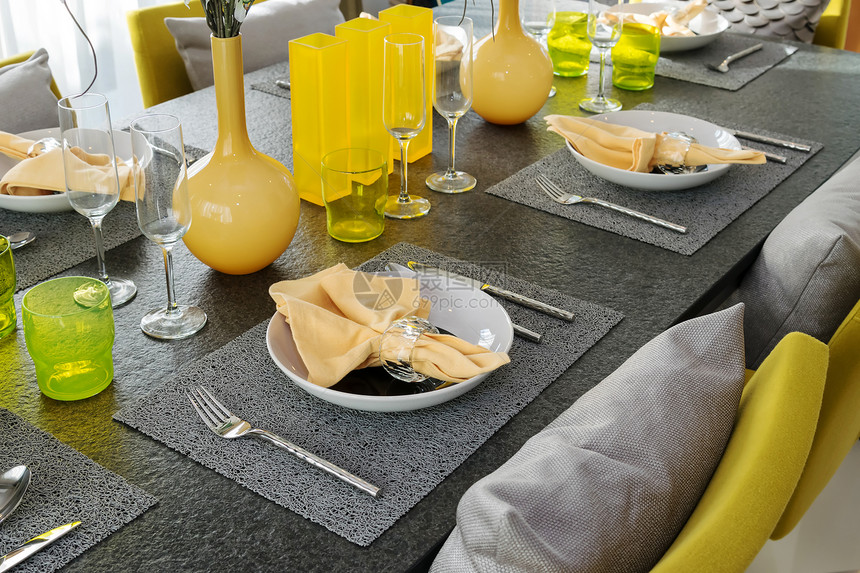 餐桌上用黄色和灰的装饰板摆着一张盘子图片