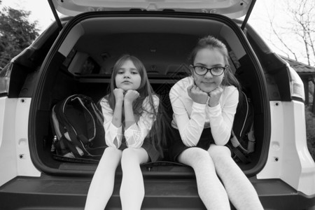 两名微笑着的女学生坐在开着的车厢里照片图片