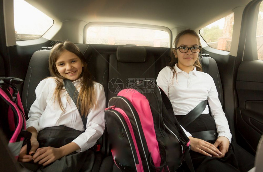两个快乐的女学生坐在汽车后座上图片