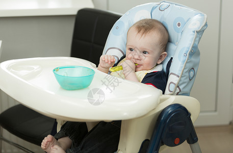 小婴儿男孩在吃饭时玩食物和菜盘高清图片