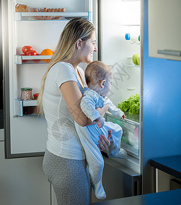 小冰箱母亲抱着儿子晚上看冰箱里面背景