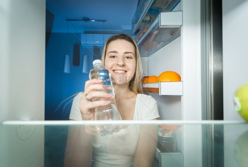 女士从冰箱里取水喝图片