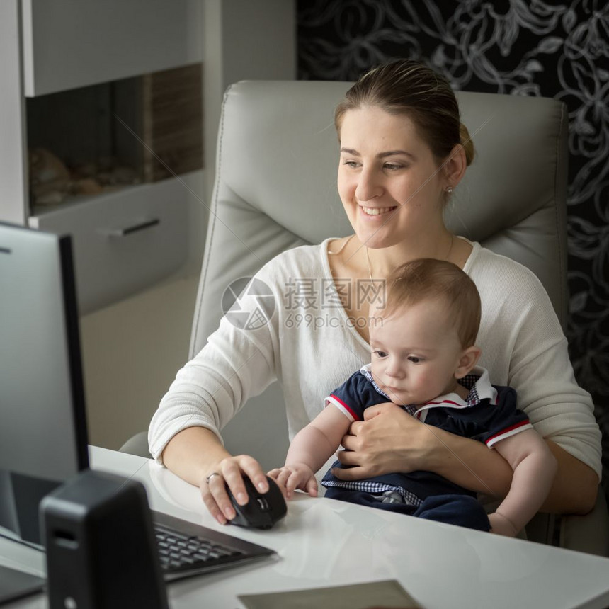 在家从事计算机工作并照顾婴儿的妇女图片