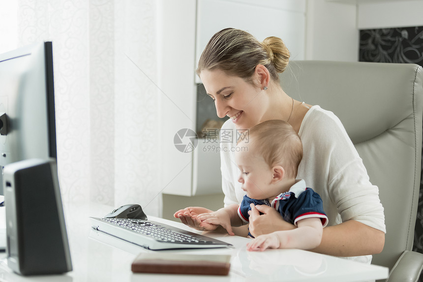 在家工作并使用计算机的有婴儿年轻妇女图片