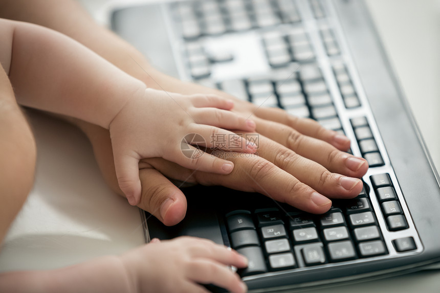 在计算机键盘上对父亲和婴儿的亲手进行关闭图片