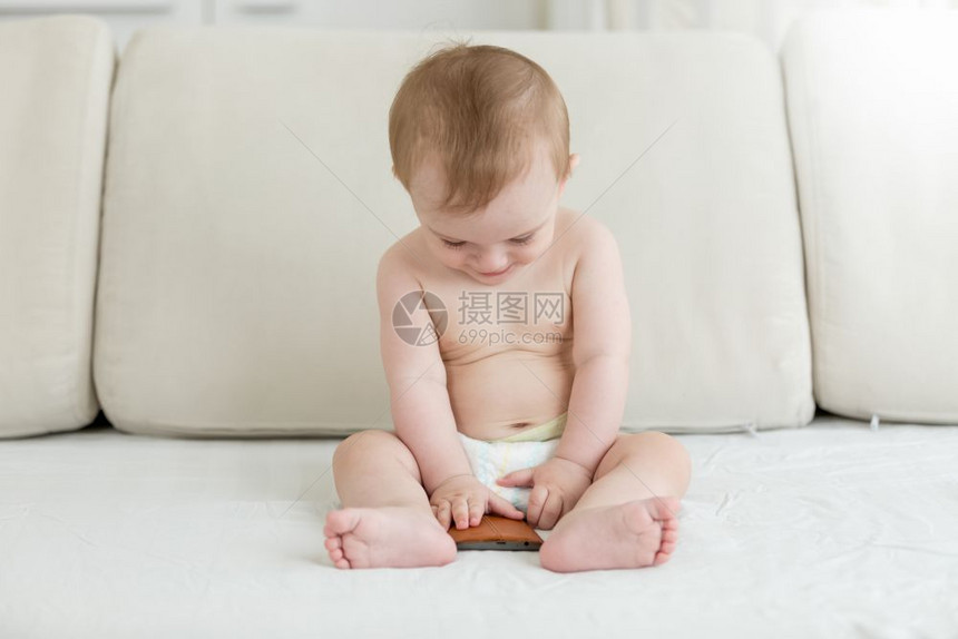 婴儿男孩坐在床上手持智能机图片
