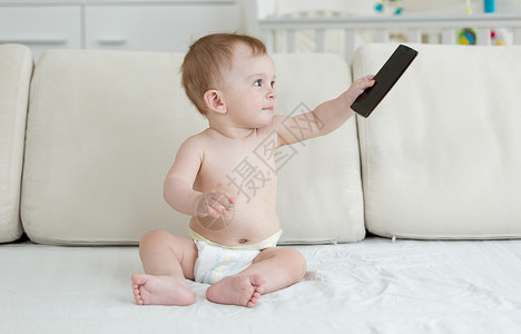 坐在床上玩智能手机的可爱婴儿图片