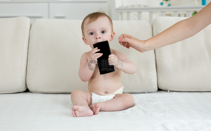 婴儿尿布坐在床上手持智能机图片