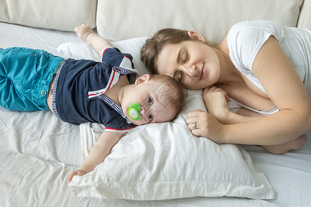 吹号子的男孩女人的肖像躺在枕头上与婴儿的子躺在枕头上背景
