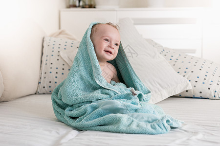 洗完澡后在蓝毛巾中裹着微笑的婴儿图片