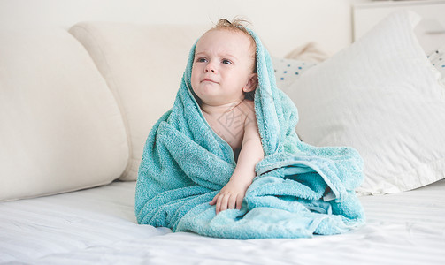 在沙发上用蓝色毯子洗完澡后可爱的婴儿男孩图片