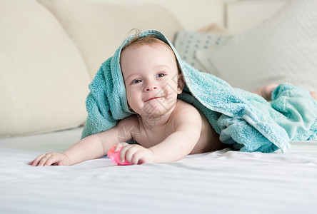 带着白床单躺在上蓝毛巾下笑着的婴儿图片
