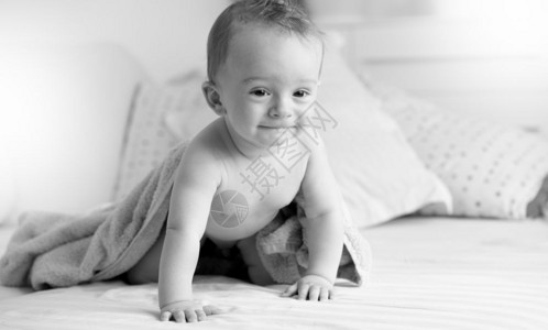 黑色和白的画面美丽9个月大婴儿男孩毛巾下躺在睡房沙发上图片
