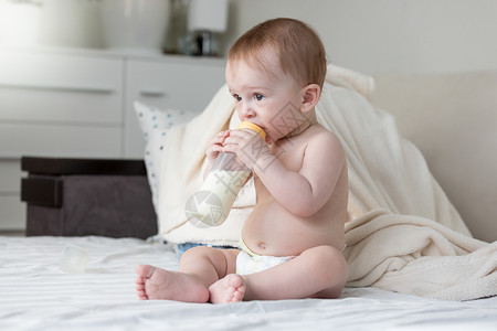 9个月大婴儿男孩坐在床上喝牛奶图片