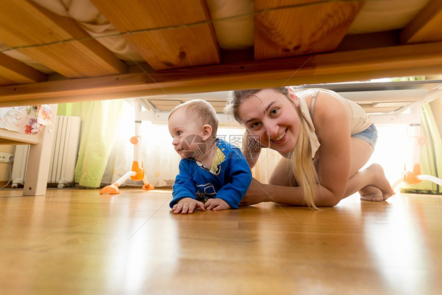 快乐的母亲和小男孩看着床底下的图片