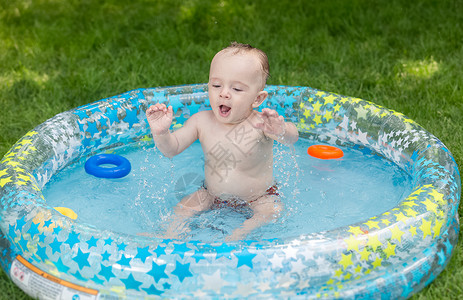 在花园游泳池玩具的婴儿男孩图片