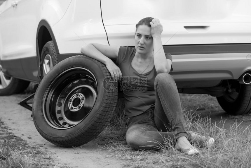 坐在轮胎旁焦虑的年轻女士图片