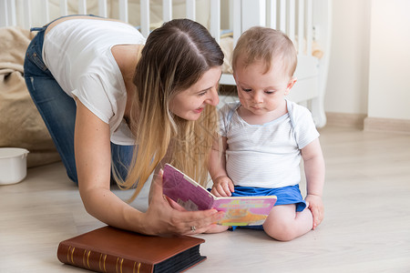 母亲在客厅的地板上读书给10个月大的孩子看书图片