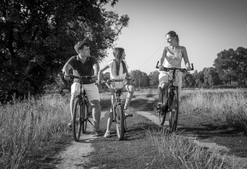 年轻家庭在草地骑自行车的欢乐景象图片