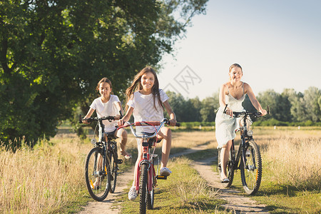 家庭在阳光明媚的日子骑自行车在草地骑自行车图片