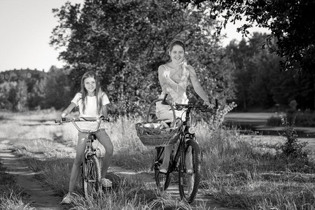 黑白一张照片美丽的快乐母亲与女儿一起骑自行车野餐图片