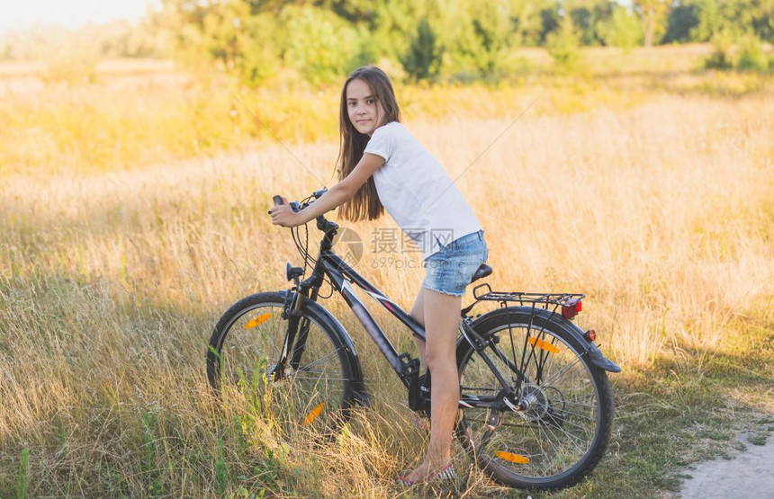 坐在草地骑自行车的美丽少女图片