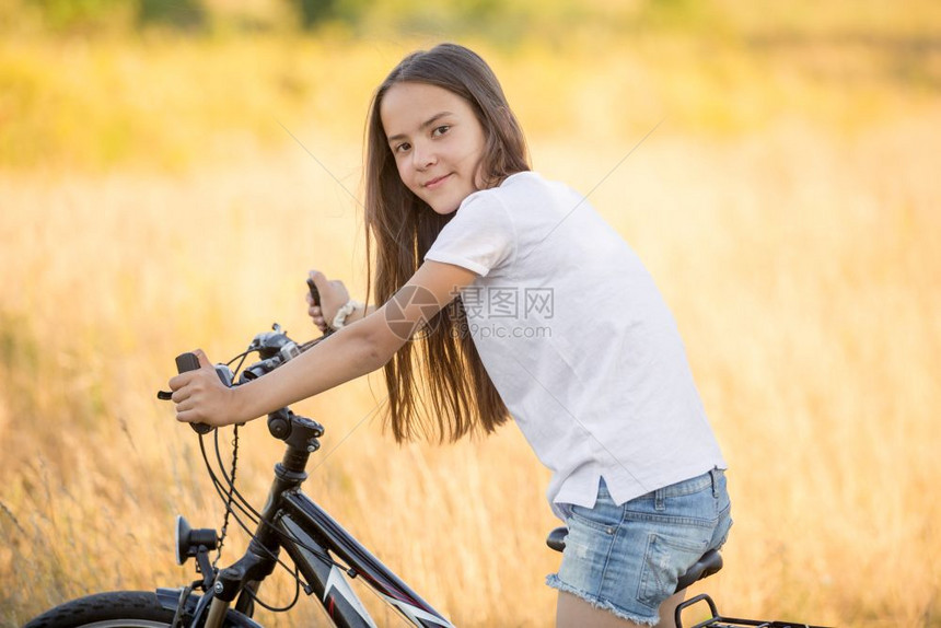 穿T恤的漂亮女孩在草地骑着自行车图片