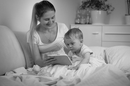 母亲夜间在床上使用平板电脑的婴儿黑白画面图片