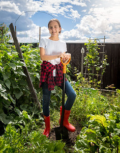 带着铲子在果园工作的微笑年轻女孩图片
