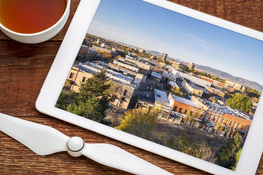 翻阅在市区的柯林斯堡数字平板电脑上的空中照片加上一杯茶图片
