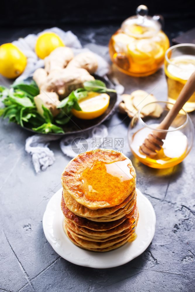 餐盘上和桌子加蜂蜜的煎饼图片