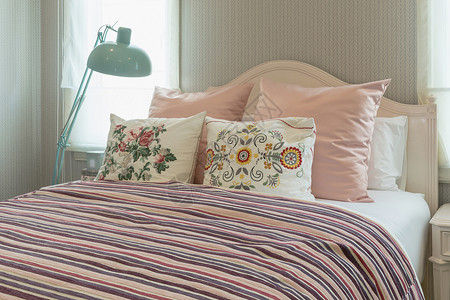 粉色柔色插图板室内古老卧床上有花枕头和粉色条纹毯子背景