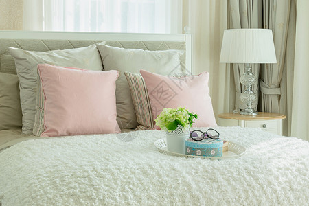 床上有粉色枕头和白花盘图片