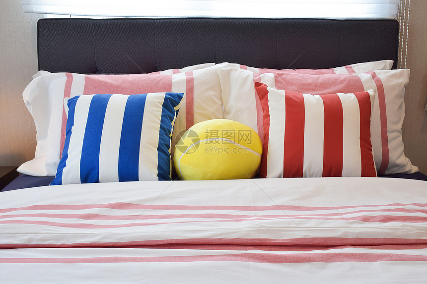 现代卧床上有蓝色和红带条纹枕头图片