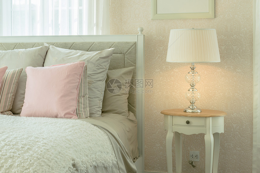 室内舒适的卧有粉色枕头和床边桌上的阅读灯图片