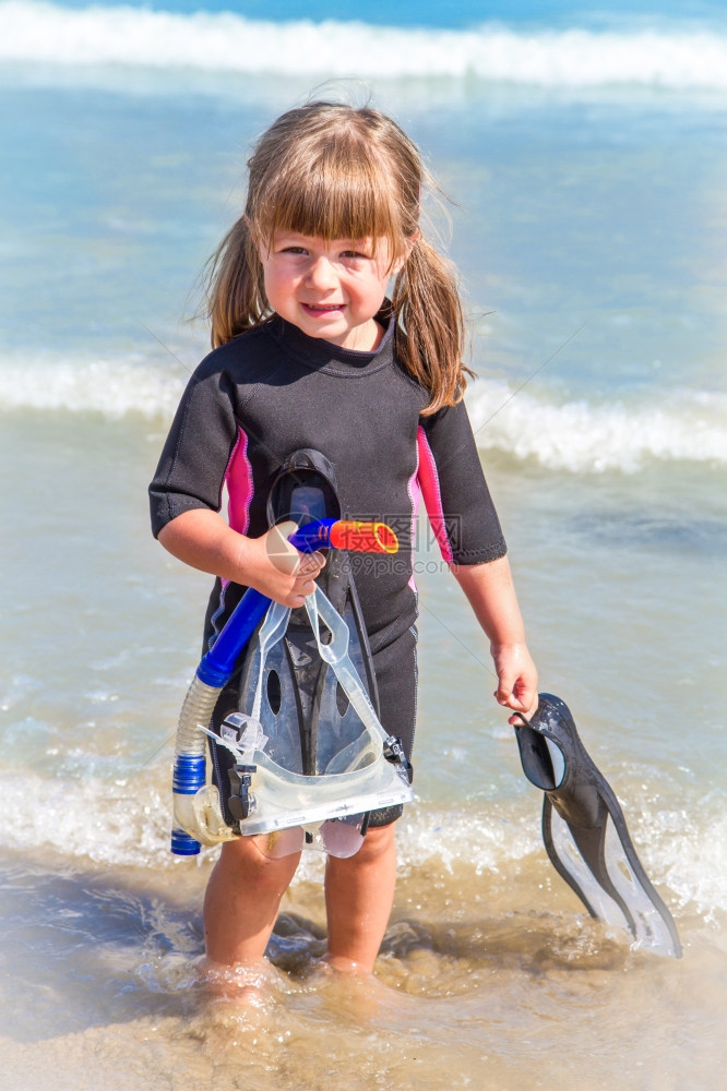 在海滩上快乐的女孩带着多彩的面罩和潜水衣图片