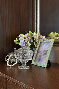 梳妆台图木制桌上有图画框和鲜花的珠宝水晶罐背景