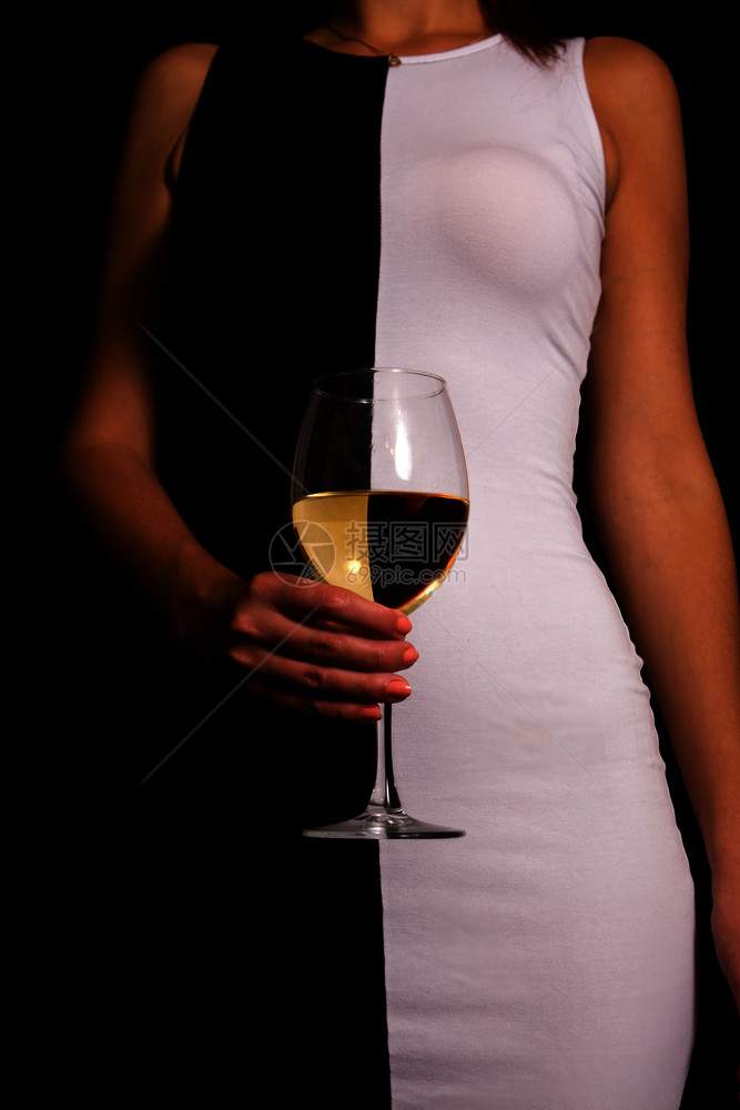 身着黑白衣服的年轻女孩手里拿着一杯白葡萄酒反射弹图片