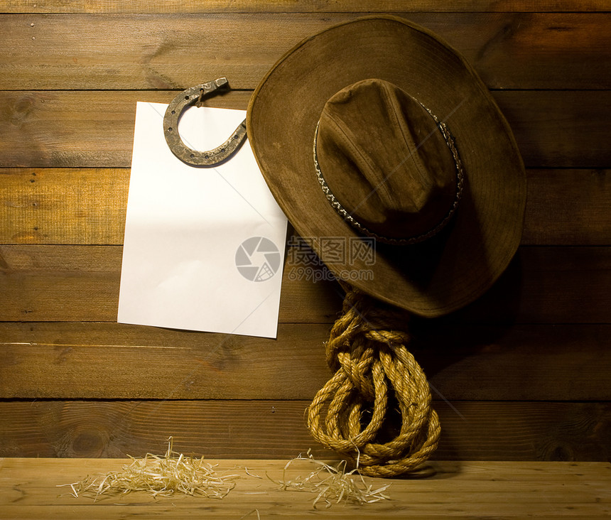 挂在旧木制牧场墙上的牛仔配件和文字空白背景图片
