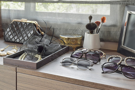手袋太阳眼镜珠宝和木制敷料桌上的化妆刷图片