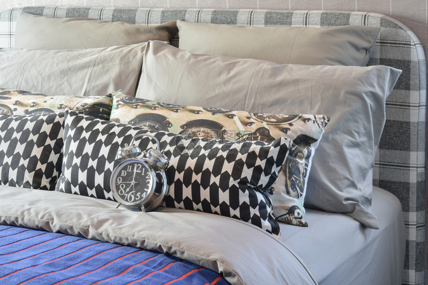 现代卧室床上有黑白枕头和闹钟图片